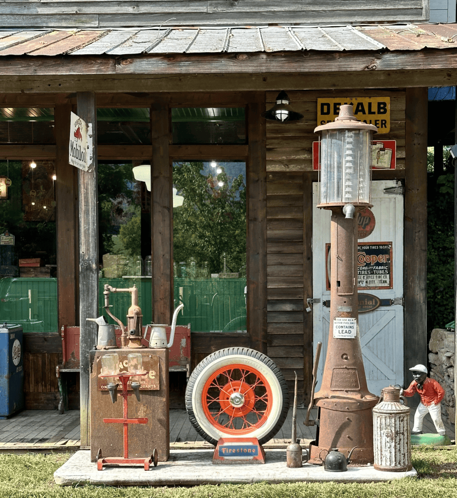 Vintage gas pumps and car wheel outside rustic wooden building.